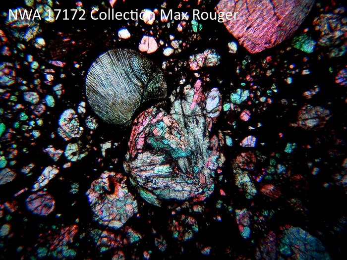 Cross-polarized transmitted light photomicrograph of a meteorite thin section with colorful chondrules in a dark matrix