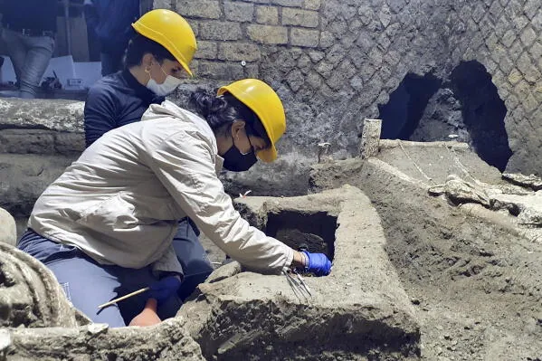 Archaeologists in protective gear work at an active Pompeii excavation site