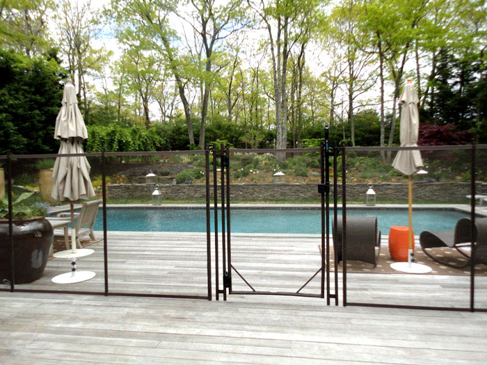 Mesh pool safety fence with a self-closing gate around a backyard pool