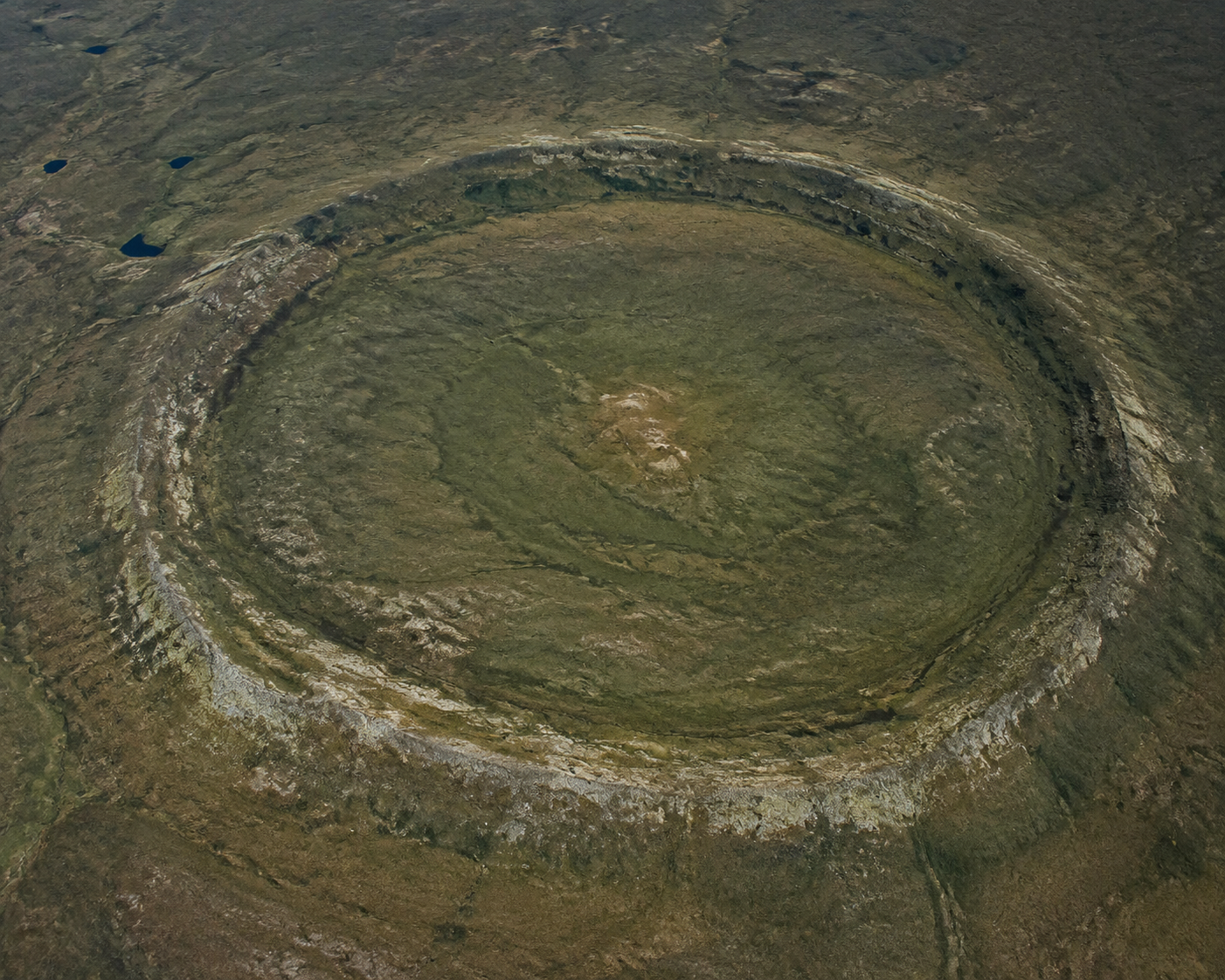 Satellite-style view of a remote landscape with a large circular depression and subtle raised rim