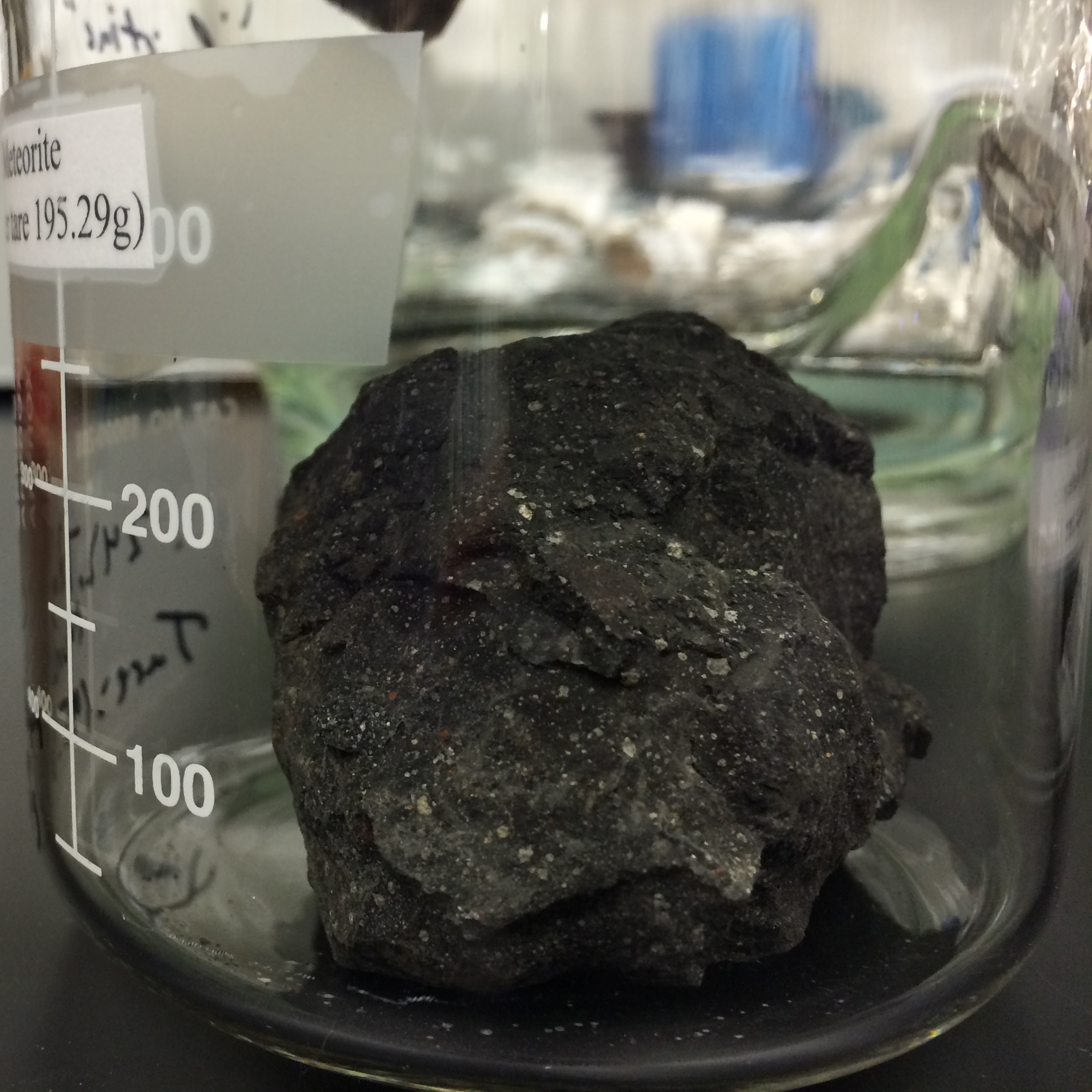 Dark fragment of the Murchison carbonaceous chondrite meteorite on a white background