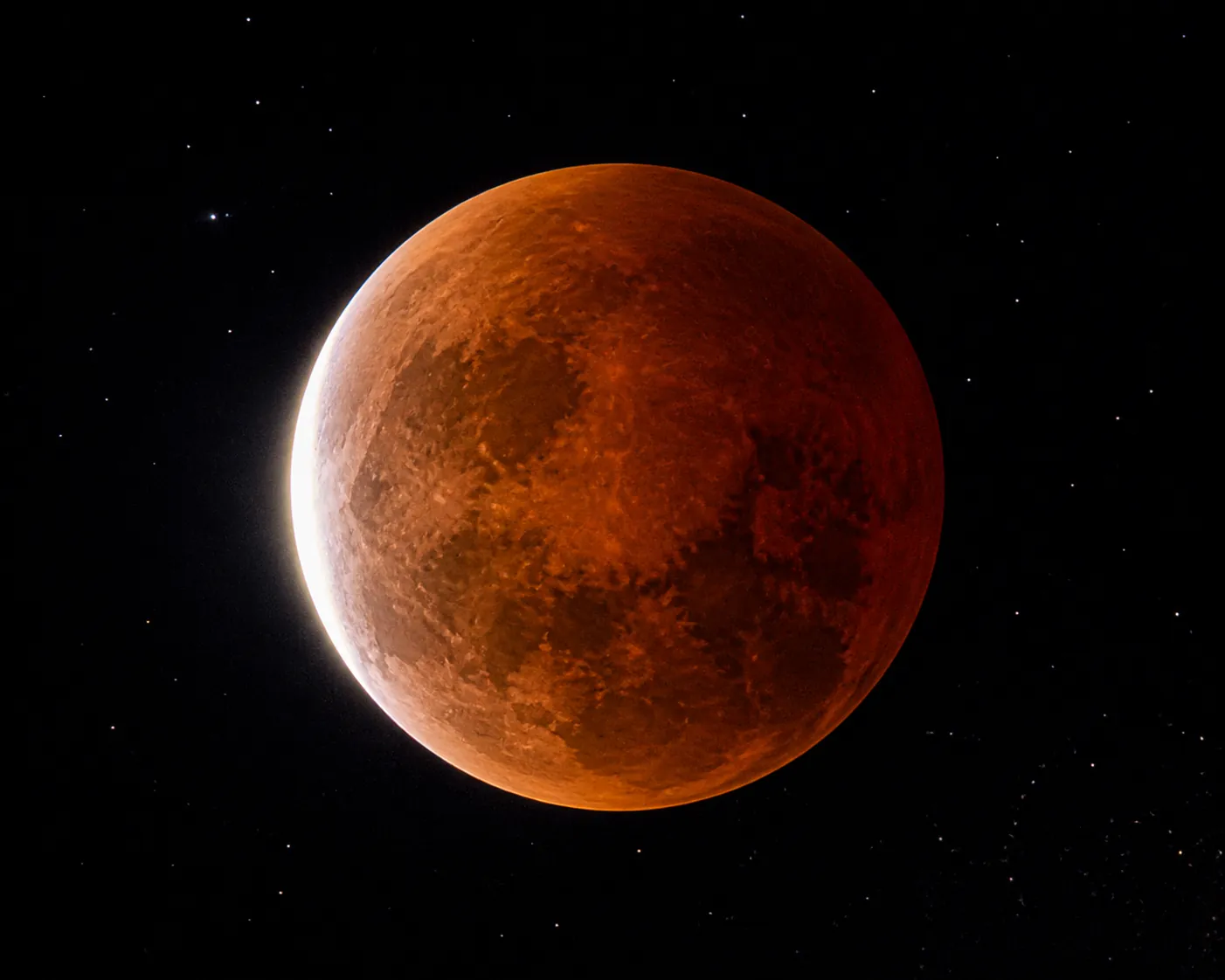 Deep partial lunar eclipse with most of the Moon covered by a reddish-orange umbral shadow